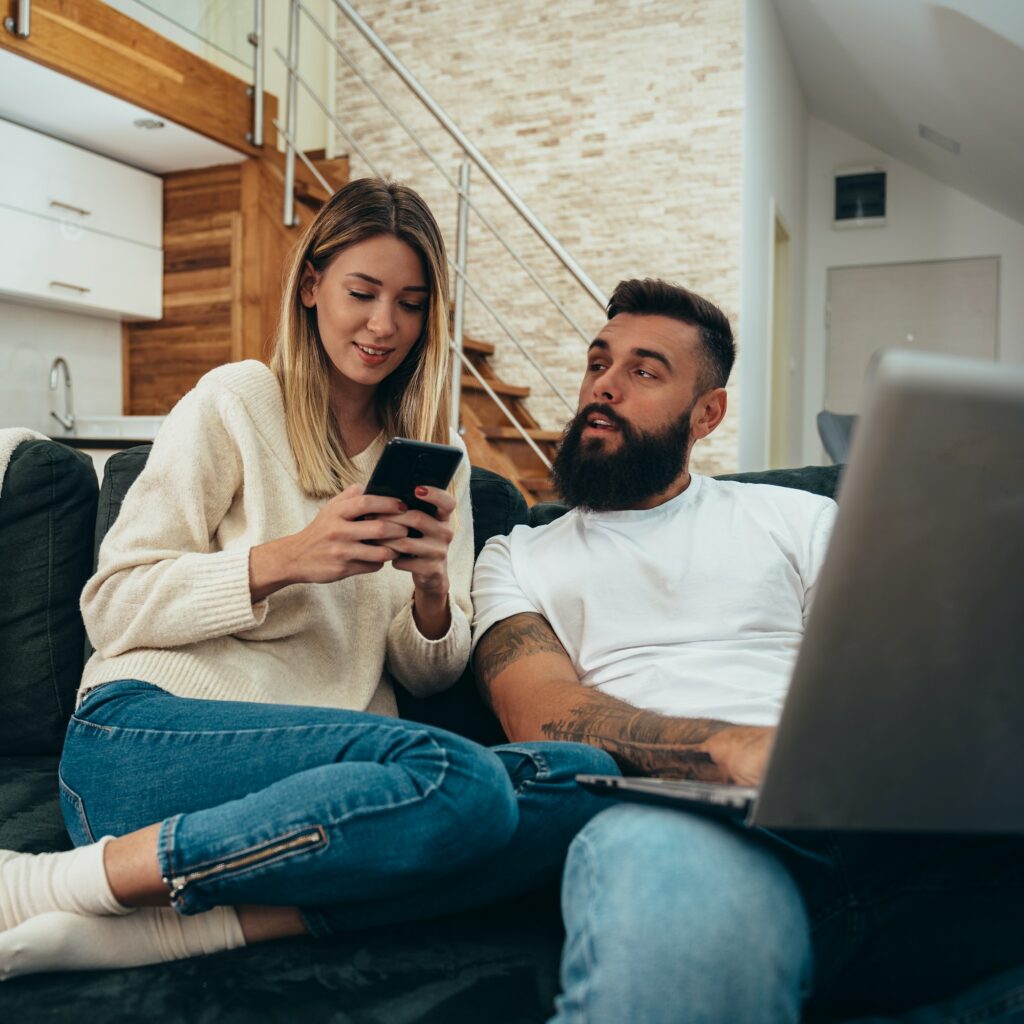 Couple using a laptop and a smartphone at home